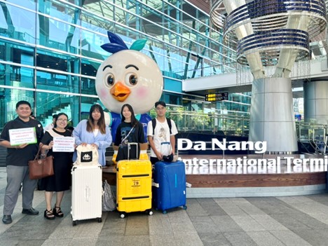 A group of people standing in front of a building with a large statue of a chickenDescription automatically generated